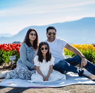 potrait of a family of three sitting on a blanket, wearing sunglasses in tulip feild