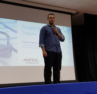 Homem em pé realizando uma palestra para uma plateia