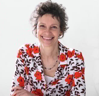 Une femme souriante, aux cheveux bruns et bouclés, elle porte un blazer fleuri, elle est sophrologue