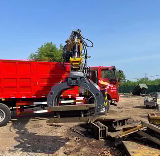 Red truck equipped with knuckle loader crane and gripper.