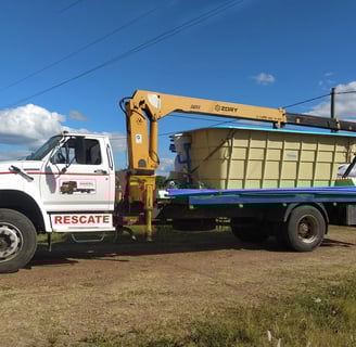 A truck with a large container on it, equipped with a telescopic boom truck mounted crane.