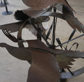a metal sculpture of a bird on a wheel