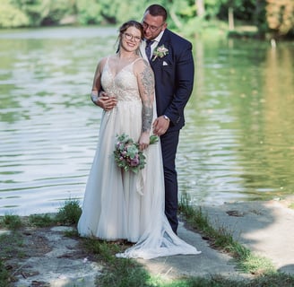 a bride and groom standing in front of a lake