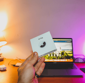 A picture of an Apple AirTag being held by a hand