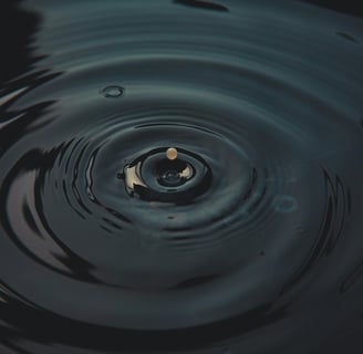 a droplet creating ripples in dark water