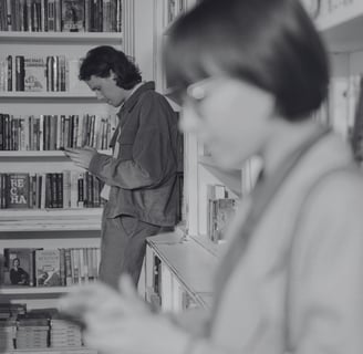 two people check their dating apps while browsing books in a quiet bookshop, showcasing slow dating