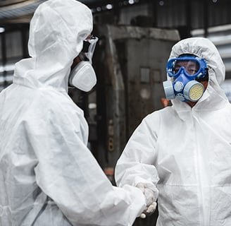 two people in white protective gear standing in a warehouse