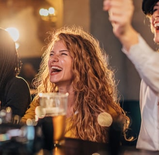 a woman is laughing and holding a beer