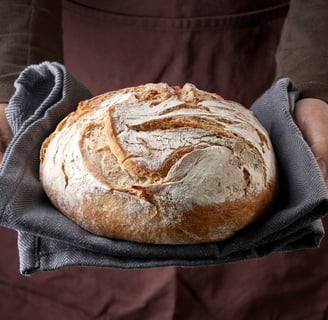 a person holding a loafed breaded bread in a kitchen