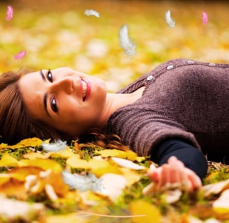 a woman laying on the ground in a field of leaves