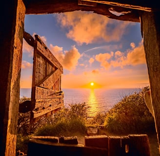 Cornish sunrise over the sea as seen though the open door of at hut at the top of a cliff