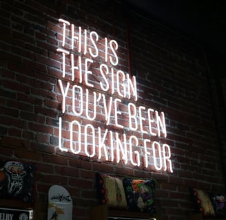 A neon sign on a wall with the text, this is the sign you have been looking for