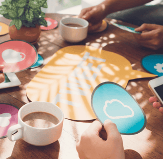 Team collaboration concept with hands holding social media icons around a table, symbolizing digital
