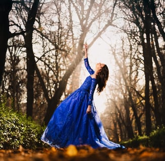 a woman in a blue dress standing in a forest