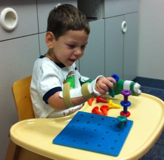 um menino sentado em uma mesa com um brinquedo