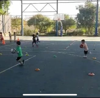 קבוצת ילדים צעירים משחקים כדורסל במגרש, בעת פעילות ספורטיבית של יום הולדת