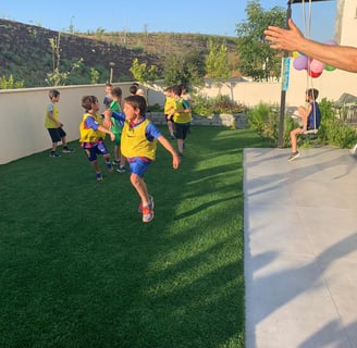 ילדים בחולצות צהובות משחקים כדורגל ביום ההולדת הספרטיבי שלהם
