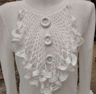 jabot sur un pull blanc deux gros boutons blanc son cousu dessus au milieu