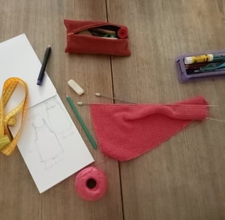 Posé sur une table un tricot et des aiguilles à tricoter un carnet à dessin des crayons une gomme