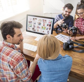 a group of people sitting around a table with cameras