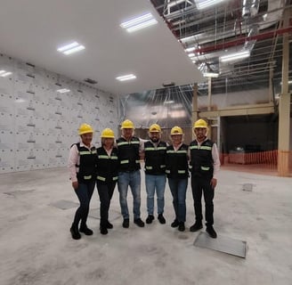 a group of men in hard hats and safety vests standing in a warehouse