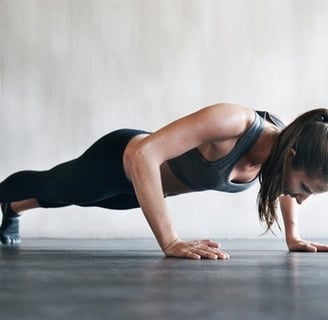 a woman doing push ups on a plank board