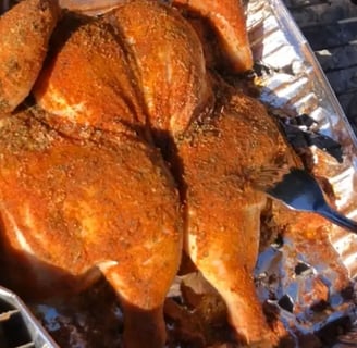 Spatchcocked whole chicken coated in homemade Cajun seasoning on charcoal grill