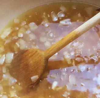 broth being stirred in dutch oven with onions garlic and smoked meat for southern cabbage recipe with smoked ham