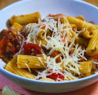 Italian sausage pasta skillet served in a white bowl with noodles on the table by a placemat