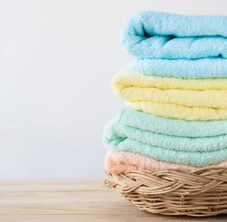 Stack of pastel-colored towels neatly arranged in a wicker basket.
