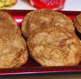 Tray of freshly baked snickerdoodle cookies arranged on a red baking tray.