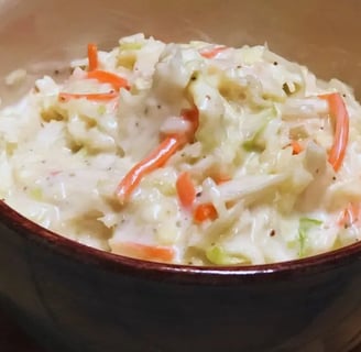 Sweet coleslaw in a blue bowl on a wooden table, creamy and ready to serve