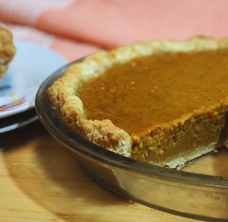Two harvest pies on a table—one whole with a slice missing and another showing a single slice of sweet potato and pumpkin pie