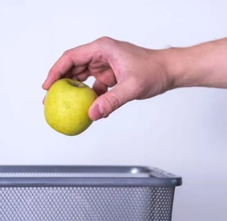 Hand tossing spoiled apple into trash can