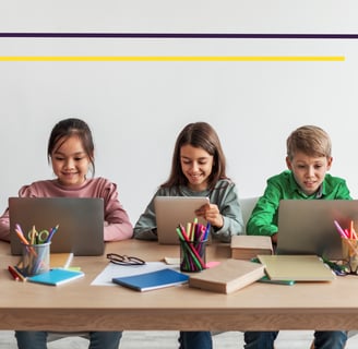 a group of children sitting at a table with laptops