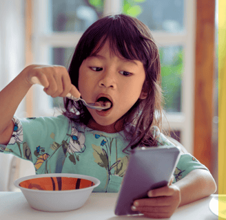 a young girl eating a bowl of soup with a spoon