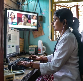 a woman in a white lab coat sitting at a computer for telemedicine