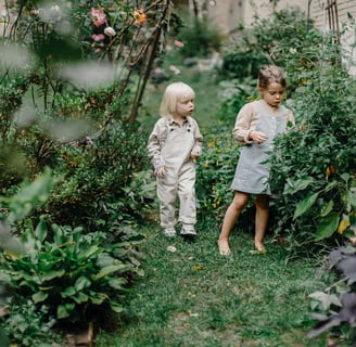 two children standing in a garden with flowers