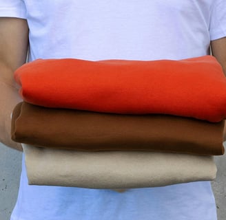 a man holding a stack of four different colored fabrics