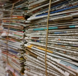 a bunch of newspapers and magazines stacked on top of each other
