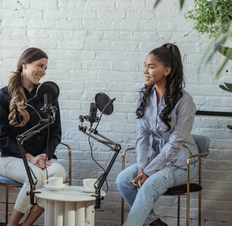 two women sitting in chairs with microphones