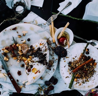 a messy table with a plate of food waste and utensils