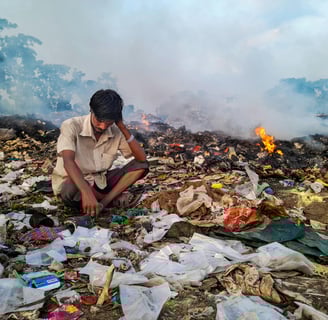 A person sitting on top of garbage while some of them are burning