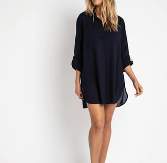 a woman in a short dress standing in front of a white wall