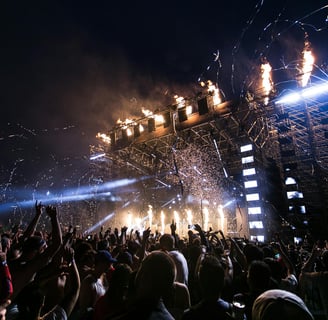 a crowd of people standing in front of a stage with fireworks