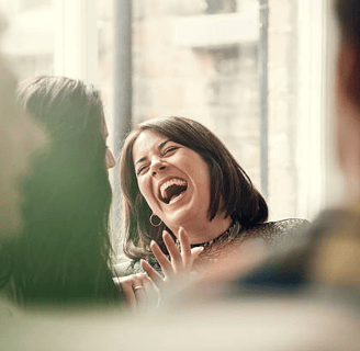 a woman laughing facing another women