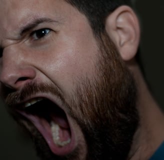 Man with a beard has his mouth wide open and is screaming