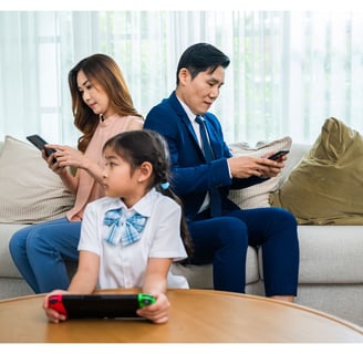Mother, Father, and Child all looking at devices.