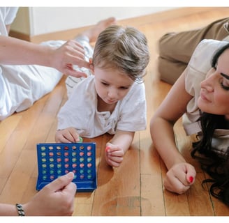 Mother and father claying Connect Four with their young child