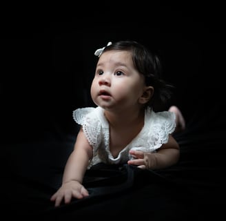 a baby girl in a white dress and a black background